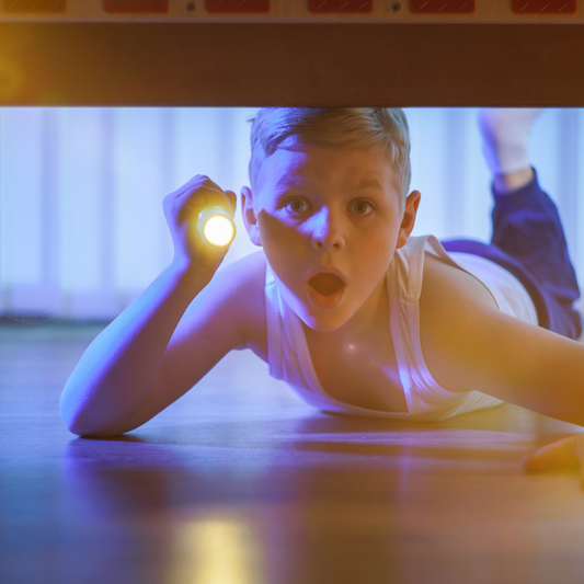 un garcon sous son lit avec une lampe